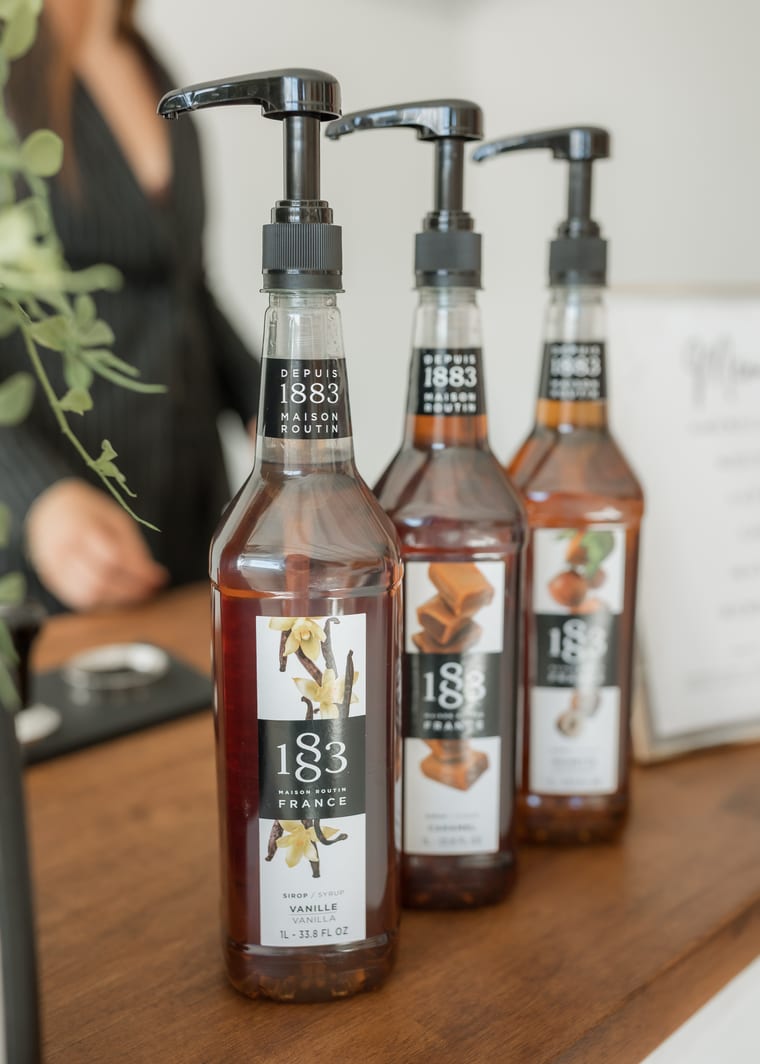 Three flavour syrup bottles with pumps lined up on the cart